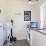 Room with washing machine, sink, and window with view of forest.