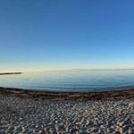 Beach with sand and calm water at sunrise.