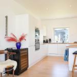 Modern kitchen with white cabinetry, wooden floor, and kitchen island with bar stools.