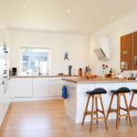 Kitchen with wooden surfaces, white cabinets, and bar stools. A corkboard hangs on the wall.