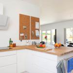 Modern kitchen with wooden surfaces and integrated kitchen island. View of dining area and garden.