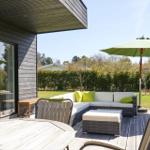 Terrace with seating, umbrella, and table. View of green lawn and hedge.
