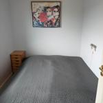 A bedroom with a bed, a wooden dresser, and a picture on the wall.