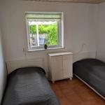 Two single beds, small cabinet, and window with garden view.