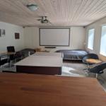 Room with ping pong table, bed, and projection screen on the wall.