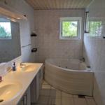 Bathroom with double sink and whirlpool bath. Window with view of greenery.