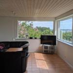 Living room with sofa, TV, and view of water and trees.