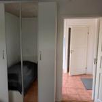 Bedroom with wardrobe and view into hallway with door.