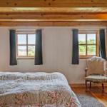 Schlafzimmer mit Bett, Stuhl und Fenstern mit Blick auf die Landschaft.