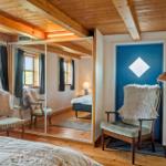 Schlafzimmer mit Holzboden, Spiegeltür und blauer Tür mit Fenster