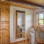 Ein Raum mit Holzwand, Spiegel, Schreibtisch und Stuhl. Fenster mit Blick auf Landschaft.