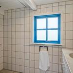 Badezimmer mit Dusche, Fenster mit blauem Rahmen und Waschbecken