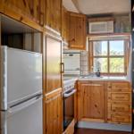 Küche mit Holzschränken, Kühlschrank, Herd und Fenster mit Blick.