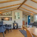 Wohnraum mit Kamin, Sofa und Stühlen unter Holzbalkendecke.