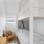 Room with bunk bed, wicker chair, and window with view of grass.