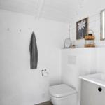 Bathroom with toilet, sink, and mirror on white wall.