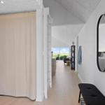 Hallway with curtain, mirror, and bench. Passage to living area with view of green field.