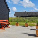 Red bench with inscription beside black house. Stone patio with planter boxes.