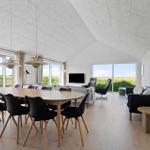 Large room with dining area, sofa, and TV. Large windows offer a view of the landscape.