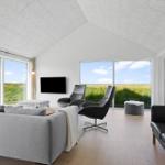 Living room with large window view of fields and TV mounted on wall.