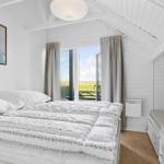 Bedroom with bed, window, and wall art. Wooden floor and white walls.