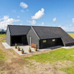 Modern black cabin with terrace, garden, and sea view.