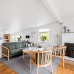 Wohnzimmer mit Sofa, Sesseln, Kamin und Fenstern.