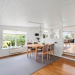 Essbereich mit Holztisch und Stühlen, großes Fenster, weiße Wände und Holzboden.
