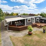 Ein modernes Haus mit Terrasse und Garten. Außentisch und Stühle sind vorhanden.