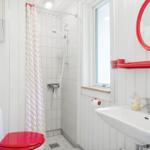 Bathroom with shower, toilet, and sink with red mirror and towel holder.