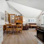 Open space with kitchenette, dining table, and living area under sloped ceilings.