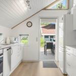 Kitchen with white cabinetry, oven, and refrigerator. Passage to terrace with table and chairs.