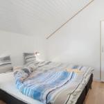Bedroom with double bed, two bedside tables and wardrobe against the wall.