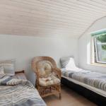 Two beds and a chair in the attic room with window.