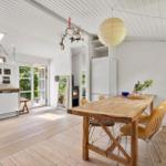 Dining area with wooden table and chairs. Kitchen and living area are open. Ceiling with shingles.