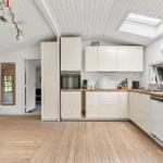 Kitchen with white cabinets, wooden floor, and skylight. Dining table and seating area in foreground.