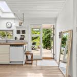 Kitchen with wooden floor, window, door to garden, and wood stove.
