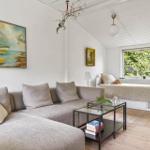 A living room with sofa, coffee table, and window view of trees.