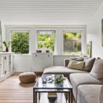 Living room with sofa, glass table, and windows to the garden.