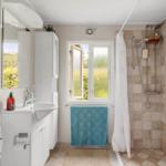 Bathroom with shower, sink, and window. Towel and mirror are present.