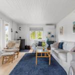 Living room with sofa, chair, table, and rug. Windows and ceiling are white.