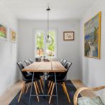 Dining room with wooden table, black chairs, and wall art