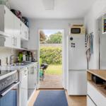 Kitchen with white built-in cabinetry, refrigerator, and view of garden.