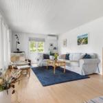 Living room with sofa, coffee table, and bookshelf. Wooden floor and blue rug.