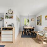 Living and dining area with wooden floor, dining table, chairs, and rattan chair.