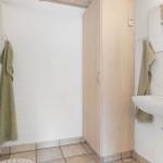Badezimmer mit Dusche, Waschbecken und Holzschränkchen.