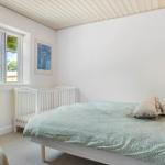 Schlafzimmer mit Bett, Kinderbett und Fenster mit Blick auf Bäume.