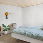 Schlafzimmer mit Bett, Holzdecke, Pflanze und Spiegel.