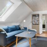 Ein Wohnzimmer mit blauem Sofa, Holztisch und Dachfenster. Holzdecke und Tür zum Flur.