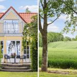 Ferienhaus mit Balkon und Terrasse. Grüne Wiese und Bäume im Hintergrund.